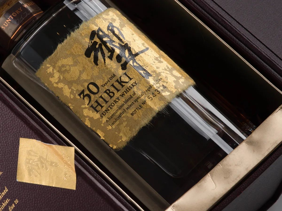 A Hibiki 30 Year Old lying in its burgundy presentation case, the gold-leaf label showing the bottle number.