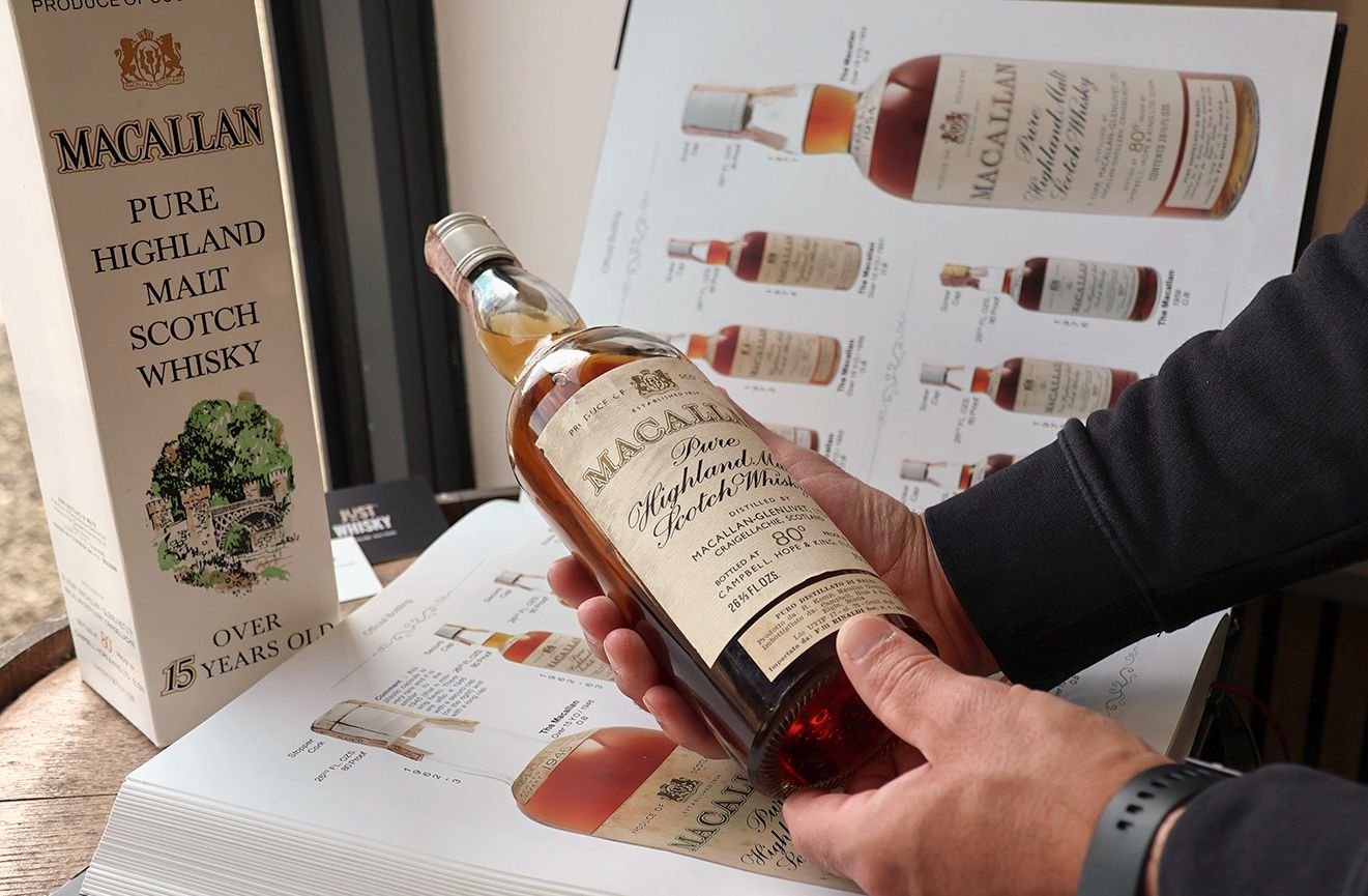 A vintage Macallan being checked against a reference catalogue at the Just Whisky saleroom.